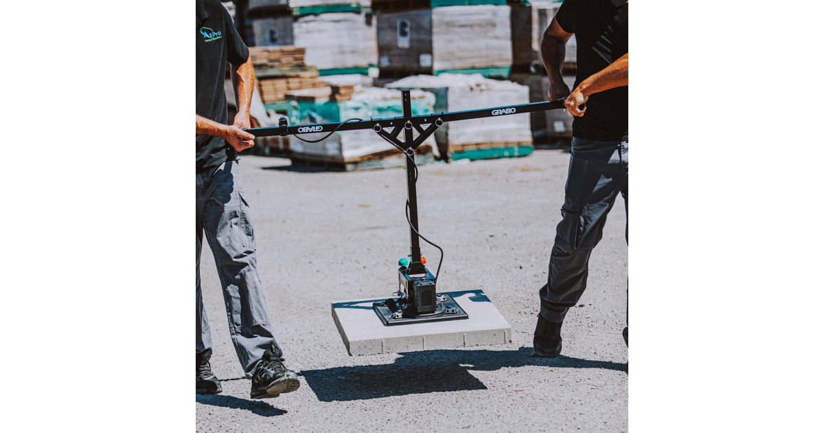Two people operating a Grabo High Flow device on a concrete surface with a white background